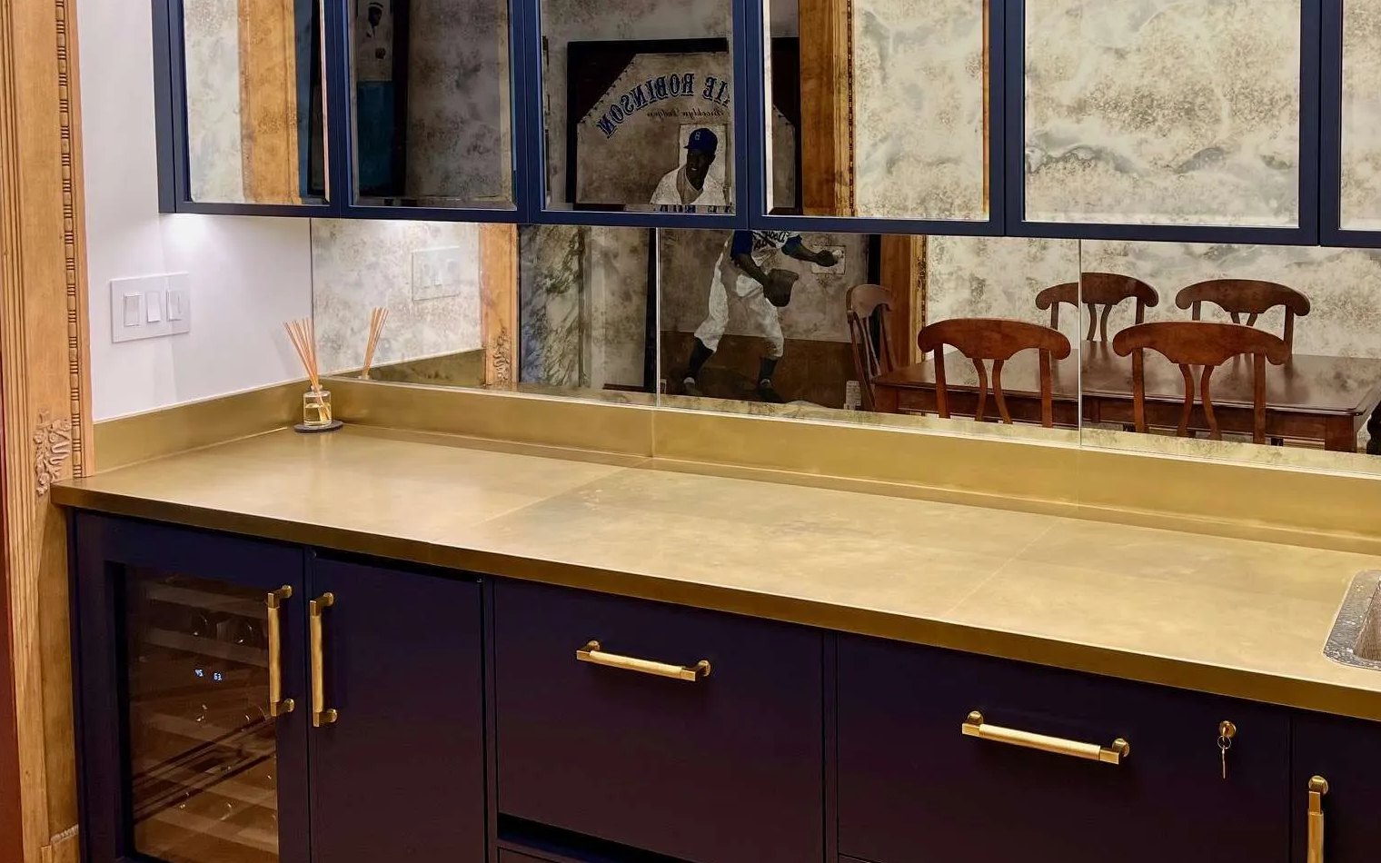 Brass countertop and backsplash on a navy wet bar with brass pulls, fabricated by Custom Metal Home