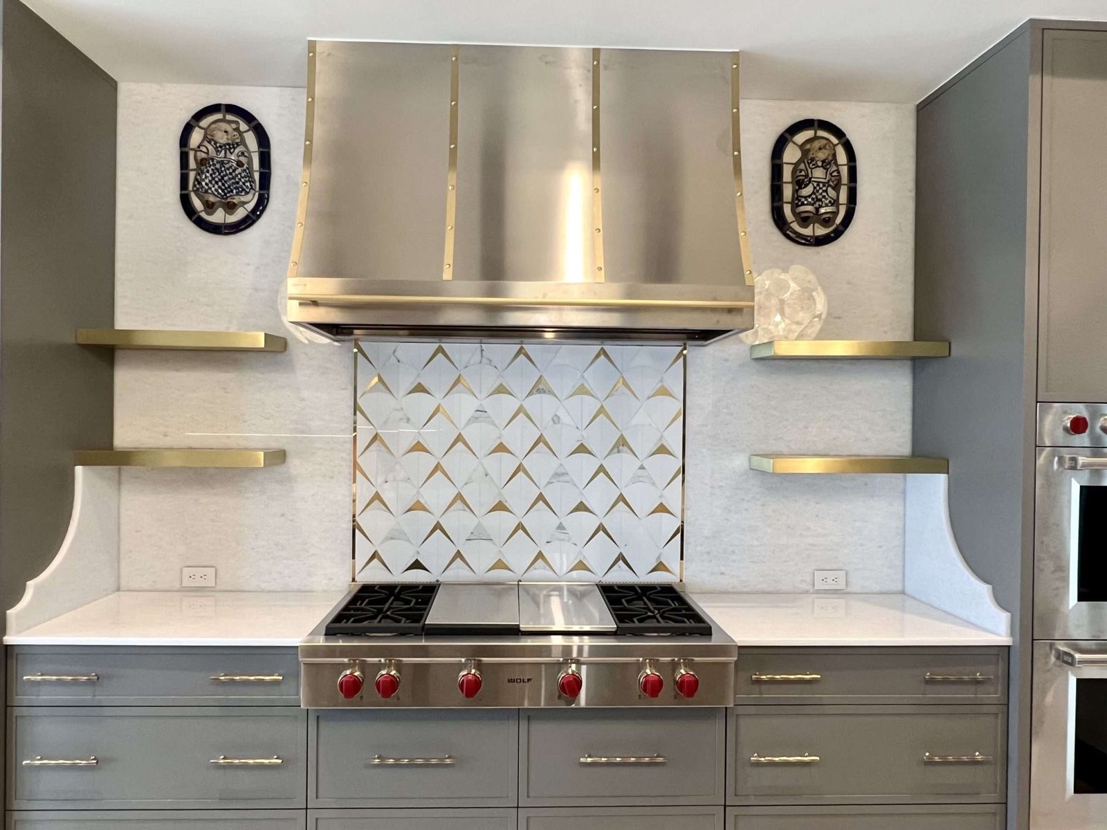 Brushed brass floating shelves beside a range hood, by Custom Metal Home