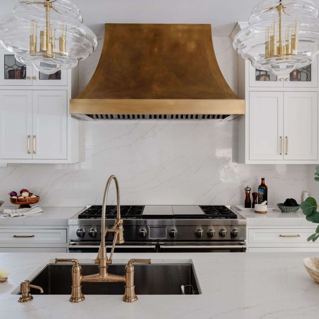 RH-5 brass range hood with a patina finish in a white kitchen, by Custom Metal Home