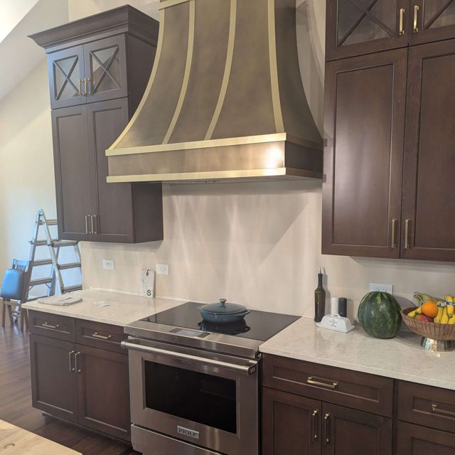 Brass range hood with matte brass straps, installed, by Custom Metal Home