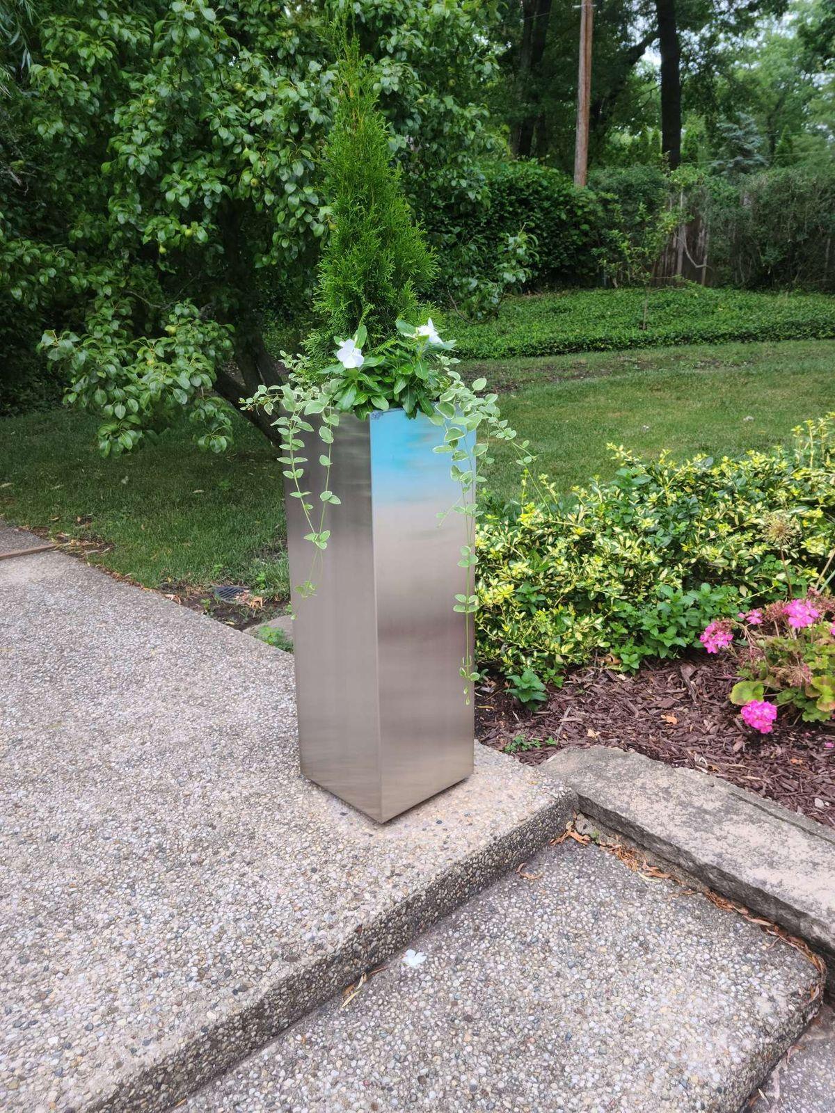 Tall stainless steel planter in a garden by Custom Metal Home