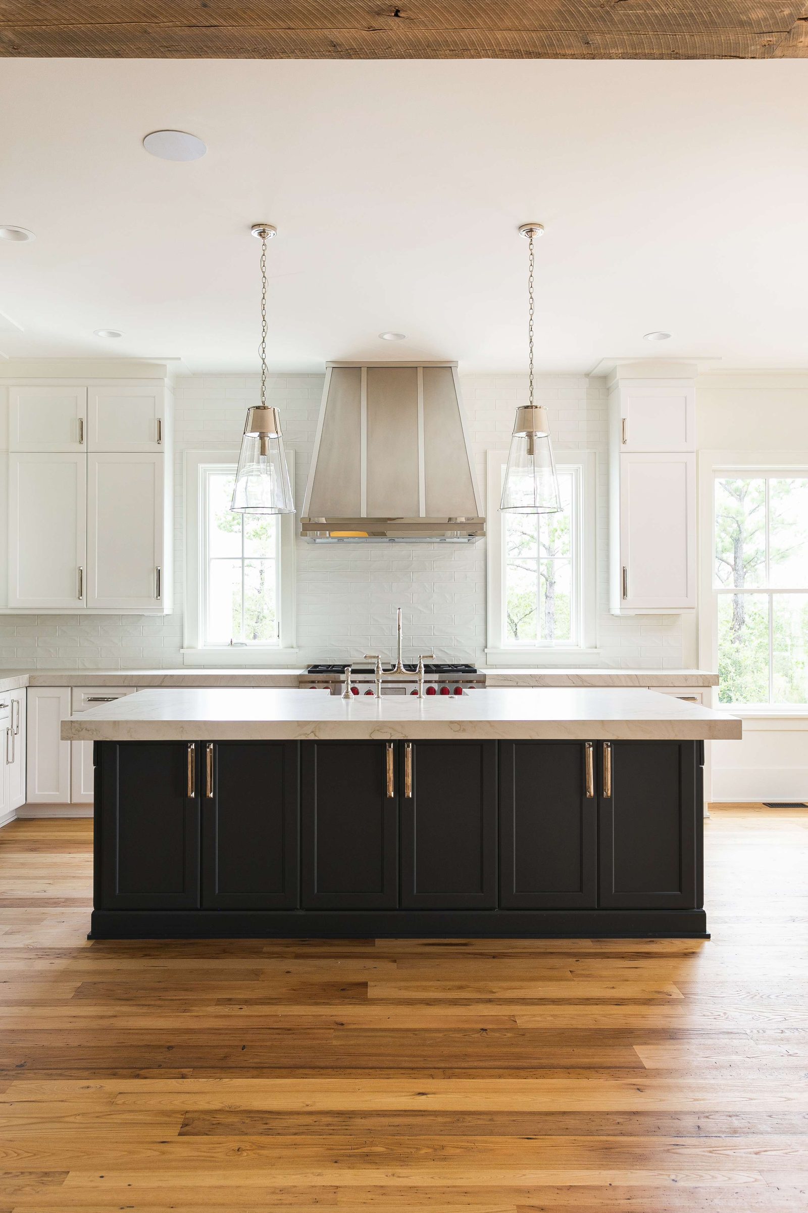 Custom metal range hood centered between pendant lights above a kitchen island, by Custom Metal Home