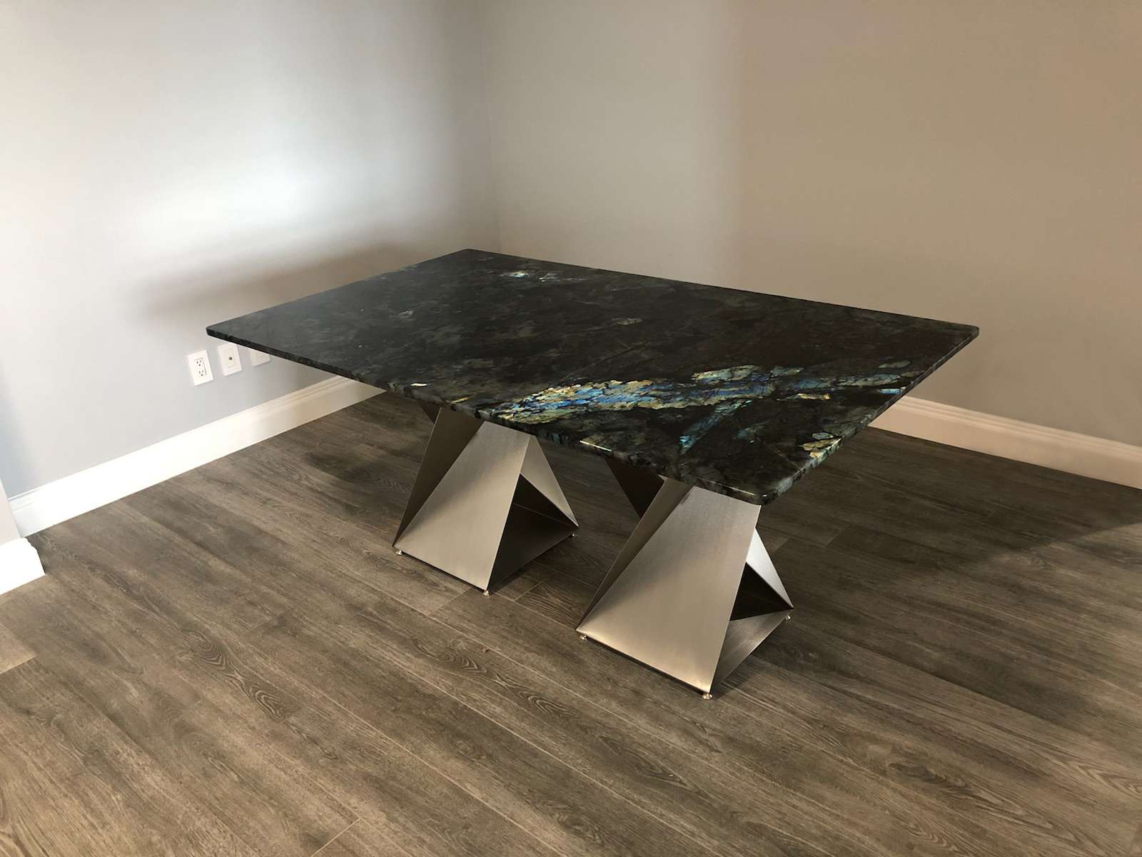 Twist table bases supporting a granite dining top, by Custom Metal Home